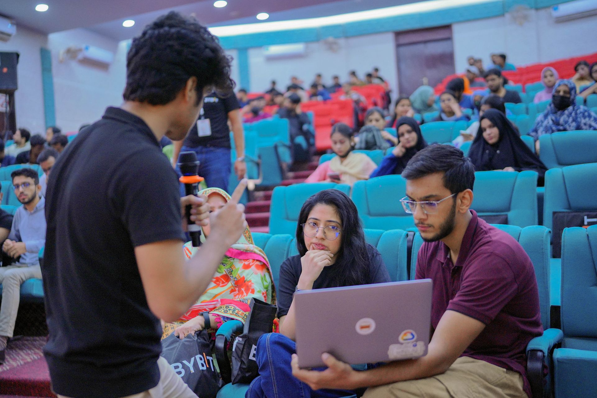 Packed lecture-hall audience of student participants at the Bybit Karachi Hackathon, with laptops, organized by CoinConnect — fulfilling minimum 50-participant deliverable
