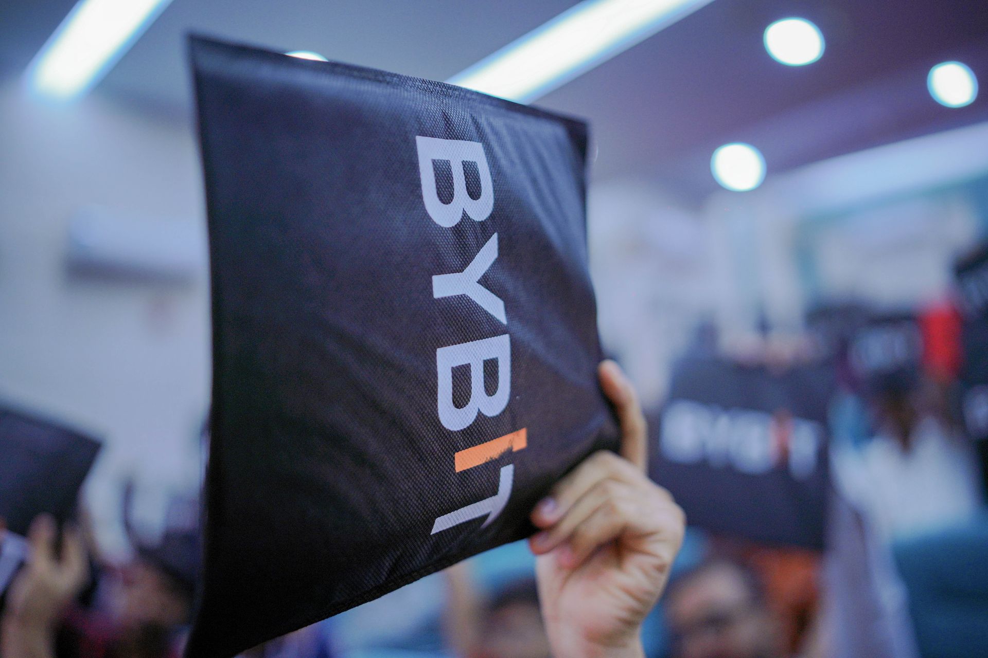 Bybit-branded event merchandise and swag bag held aloft at the Pakistan activation event organized by CoinConnect